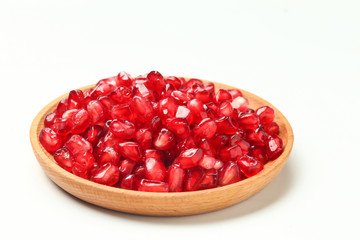 pomegranate seeds in wooden plate isolated on white background