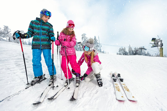 Mom with children on ski terrain preparing daughter for skiing