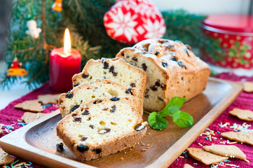 Sliced christmas fruitcake with raisins on festive background