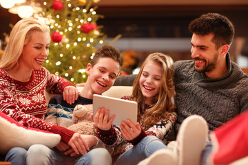 Christmas time- family watching funny video on digital tablet. - obrazy, fototapety, plakaty
