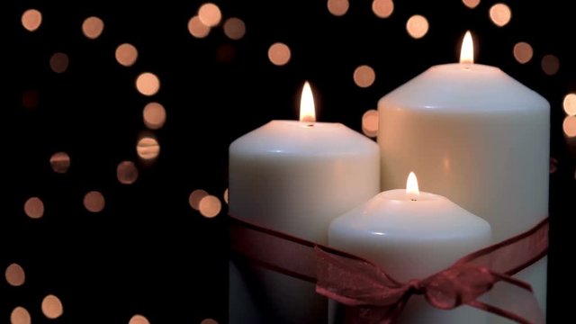 Christmas candles with red ribbon burning in atmospheric light. 4k