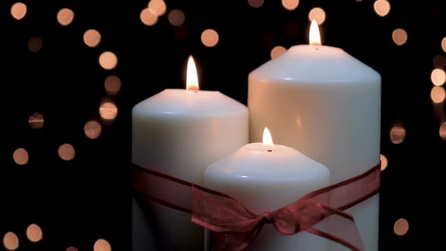 Christmas candles with red ribbon burning in atmospheric light. 4k