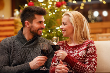 couple celebrating Christmas toasting with glasses of red wine.