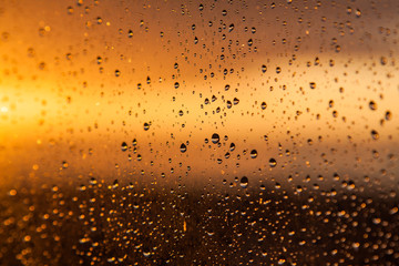 Rain drops on a window at sunset