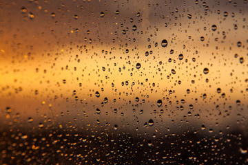 Rain drops on a window at sunset
