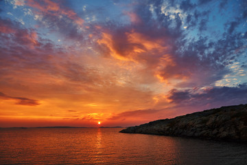 Beautiful colorful sunset at the sea with dramatic clouds and sun shining.