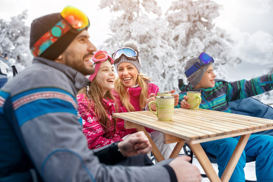 Family laughing and takes tea break during skiing on the mountain