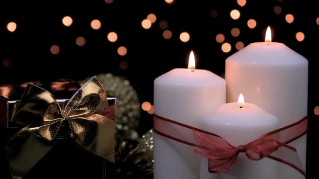 Christmas gift and candles with red ribbon burning in atmospheric light. 4k
