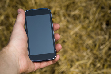 cell phone in hand on the background of wheat