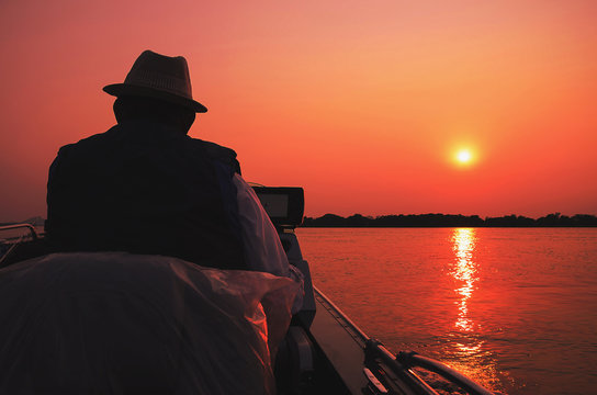 Fisherman navigating in his boat at Pantanal on a golden hour sunset