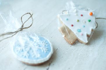 Two Christmas gingerbread cookies in the different shapes in a cellophane packing on a wooden table.