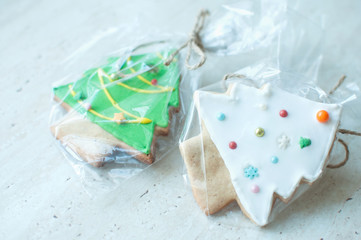 Two Christmas gingerbread cookies in the shapes of Chrismas trees in a cellophane packing on a wooden table. Christmas gift concept.