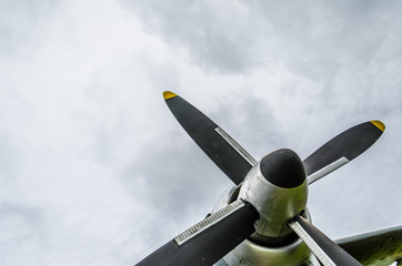 Naklejka na ściany i meble Close up of airplane turboprop engine with propeller, parts of aircraft fuselage, wings and tail on a cloudy sky background