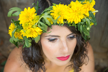 Dreamy young woman in yellow dress with wreath made of yellow flovers
