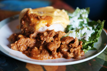 Thai Food Panaeng Curry with Pork and omelet on cooked rice in white plate
