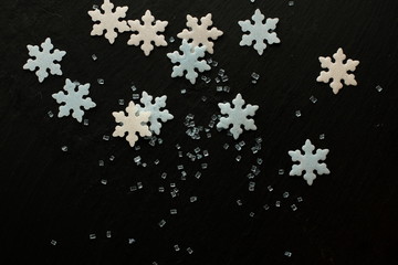 White and blue sugar snowflakes with blue sugar crystals on black background