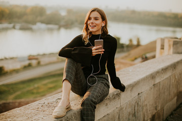 Trendy young woman listening music from smartphone outdoor