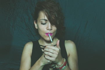 Obraz premium Abstract dark portrait of beautiful young girl with messy hair holding and lightning cigarette