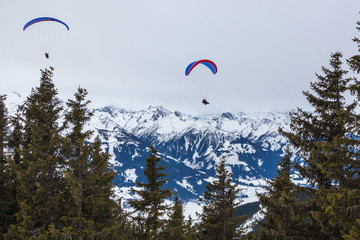 Paragliding above Alps covered with snow near Zell am See, Austria