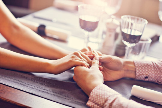 Couple Eating Romantic Dinner In A Gourmet Restaurant Drinking Wine And Holding Hands