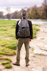 backside of bavarian man with backpack and standing by river