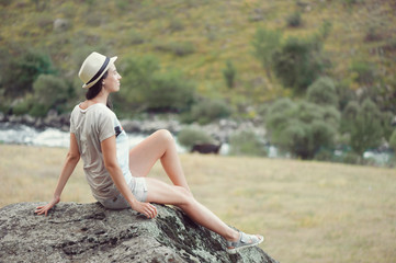 Young woman siiting on the stone outdoors and relax