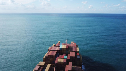 Huge large mega ULCV container ship sails on open water fully loaded with containers and cargo - aerial view