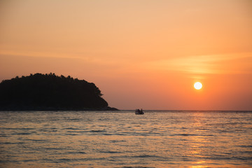 Small island and boat at sunset