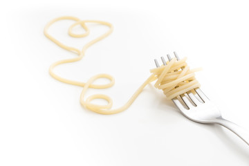 Plain cooked spaghetti pasta on fork with heart shape, on white background.