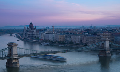 Fototapeta premium Parliament in Budapest in early morning and a big boat under the bridge through river Danube 