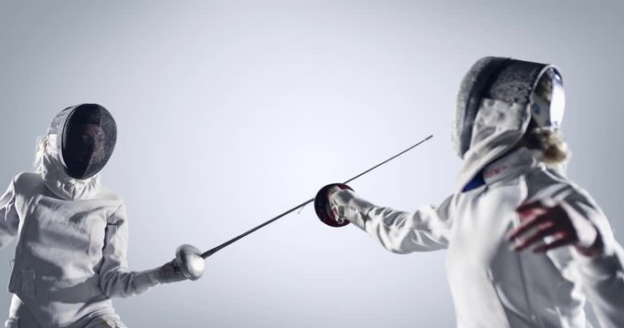 Two fencing sportswomen  in action on white background