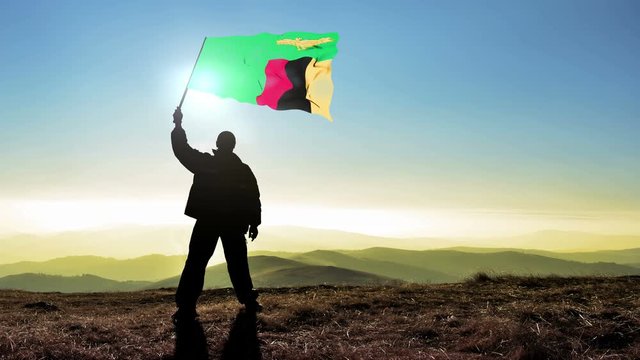 Successful silhouette man winner waving Zambia flag on top of the mountain peak, Cinemagraph LOOP background
