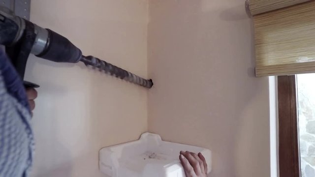 Worker man drill the wall with heavy large jackhammer drill. Making a hole for air conditioner pipes instalation