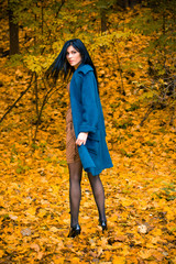 Portrait of young beautiful woman in autumn blue oversized coat. Brunette fashion woman walking outdoor against an autumn nature landscape High fashion photo of elegant woman stylish in boho style