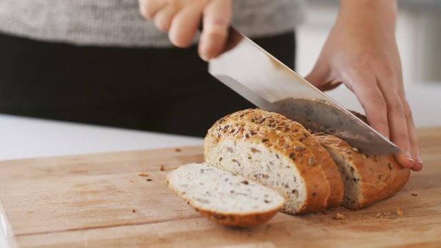 close up of hands cutting white bread with knife