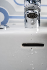 a tap with water coming out in a bath with.  tiles
