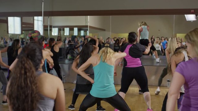 Medium panning shot of instructor leading exercise class / Orem, Utah, United States