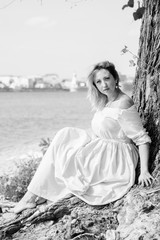 Fototapeta na wymiar Beautiful and natural portrait of female by the river port. Happy woman plus size standing at the seaside and looking away. Concept of harmony on weekend at city