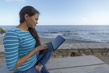 An Asian woman is working with laptop on a beach