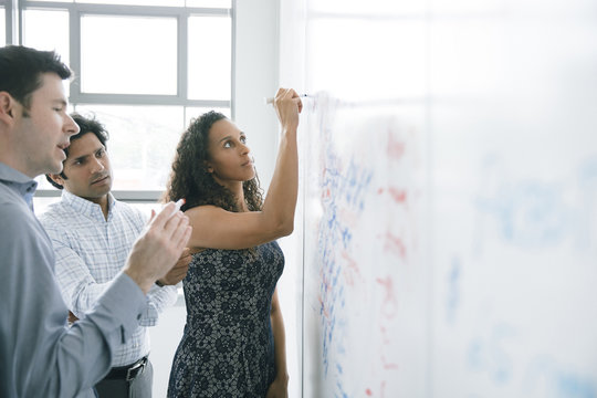 Businesswoman writing on whiteboard in meeting