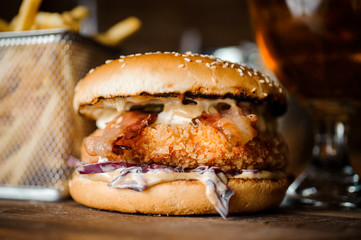 Tasty burger with cutlet, cheese and vegetables served on a wooden table
