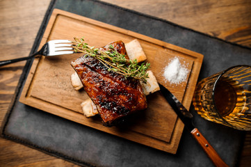 Wooden plate of tasty grilled rib with golden crust