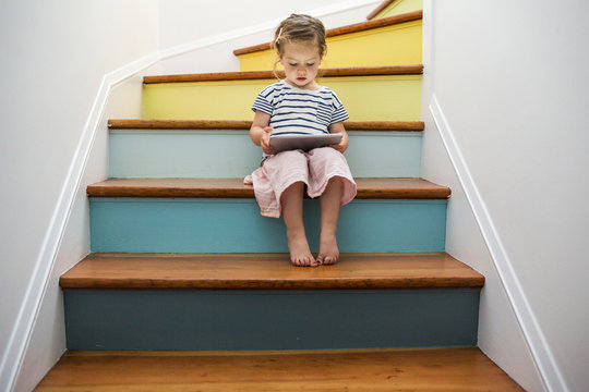 Girl using digital tablet on staircase