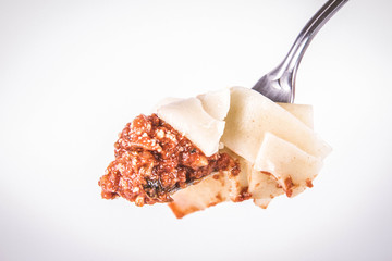 Pappardelle with bolognese sauce on a fork on a white background