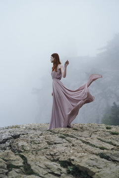 Woman wearing dress on rock in fog