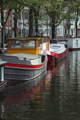 Fototapeta na wymiar Boats moored to the shore at the canal of Amsterdam