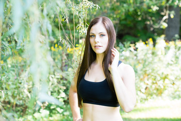 Fototapeta premium Portrait of a fit woman in a park exercising with beautiful green forest in background