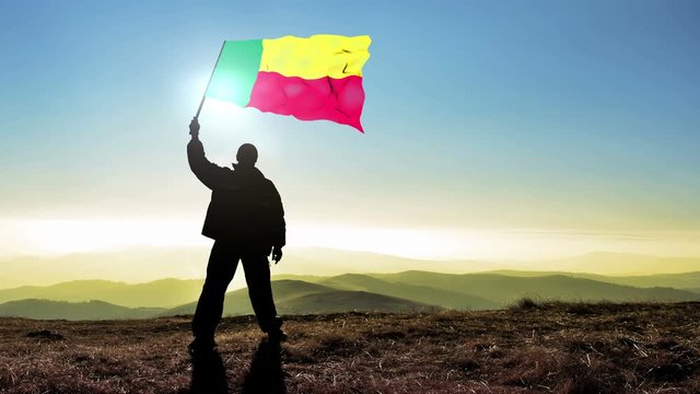 Successful silhouette man winner waving Benin flag on top of the mountain peak. Cinemagraph LOOP background