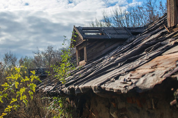 An old abandoned ruined wooden building. A roof of a destroyed house. Old attic with window