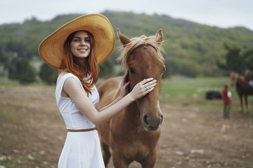 Young woman stroking horse muzzle in field
